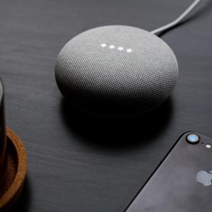 a google home sitting on a desk next to an iphone