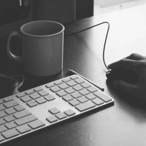 a keyboard and mouse with a coffee mug next to the keyboard