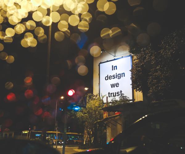 a lit billboard that says "in design we trust"
