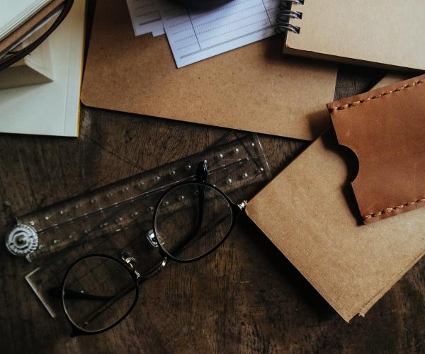 a desk workspace with cardboard, a ruler and a notebook on it