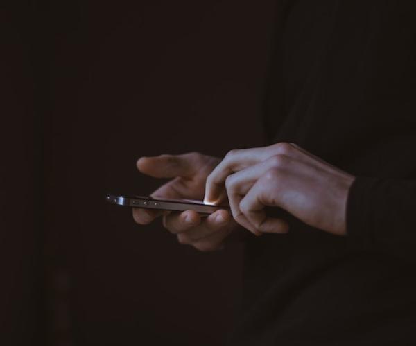 a dark photo of two hands holding a phone