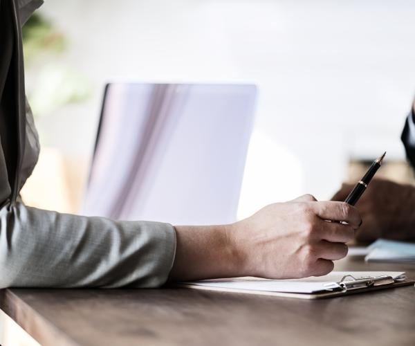 a person sitting at a desk writing in a notepad
