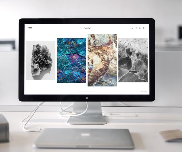 front view of an imac with 4 images on the homescreen. a closed macbook sits in front of it