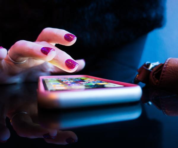photo of a person with painted nails tapping on a phone