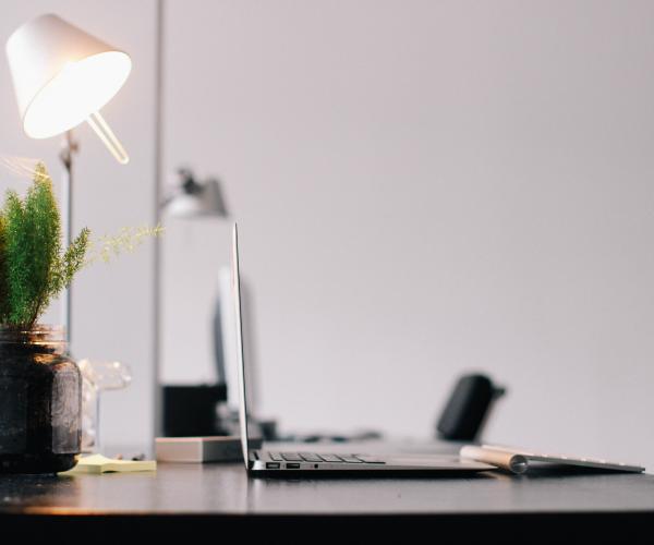 photo of a desk with a laptop and a lamp on top