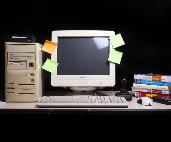 an old computer turned off with sticky notes of various colors attached to the screen