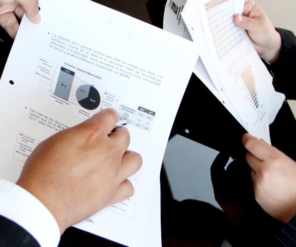 2 people holding pieces of paper with stats on them