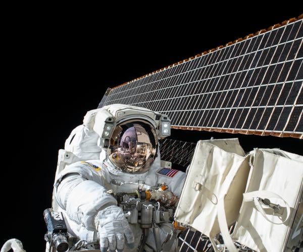 an astronaut holding onto part of a space station