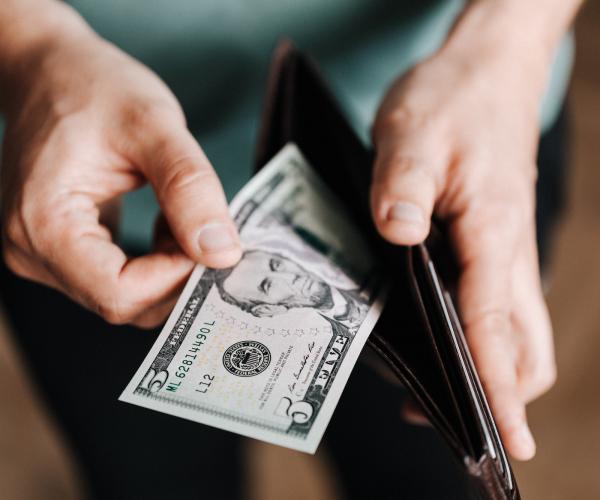 a person pulling a 5 dollar bill out of their wallet