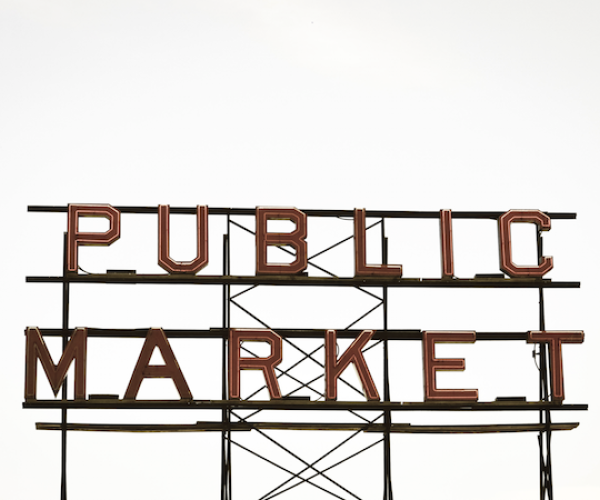 a neon sign that's off that says "public market". the background is a white sky.