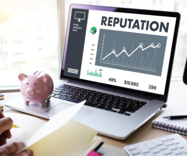 an open laptop with the word "reputation" on it with some stats below it. a piggy bank is next to the laptop