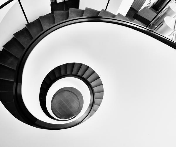 the top of a black spiral staircase contrasted to a white wall around it