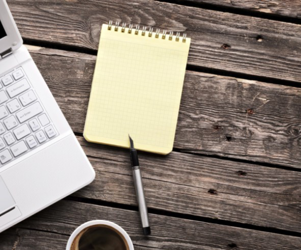 a laptop and an empty notepad laying flat next to each other