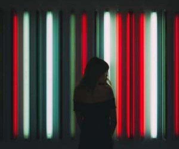 person stands in front of a plethora of lights. the person is a shadowed silouette.