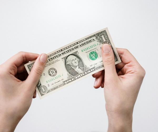 Person holding a one dollar bill.
