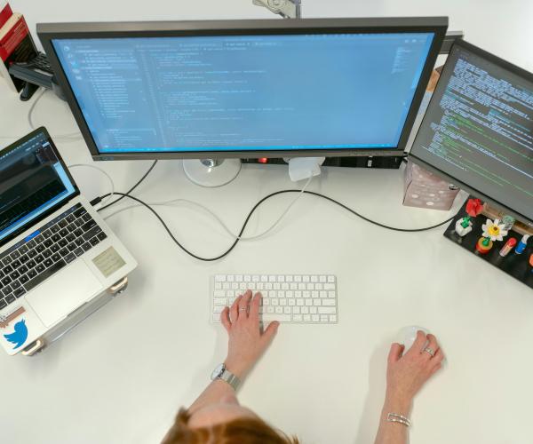 Person at a computer writing out code for a program or application.