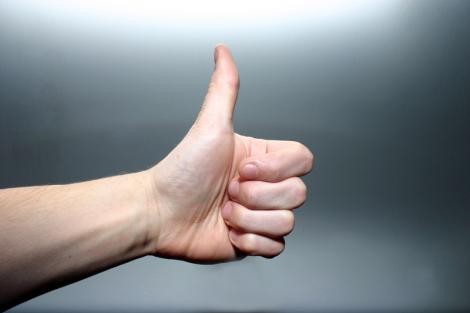 someone holding their left thumb in the thumbs up position