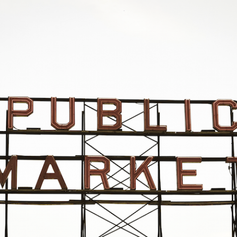a neon sign that's off that says "public market". the background is a white sky.