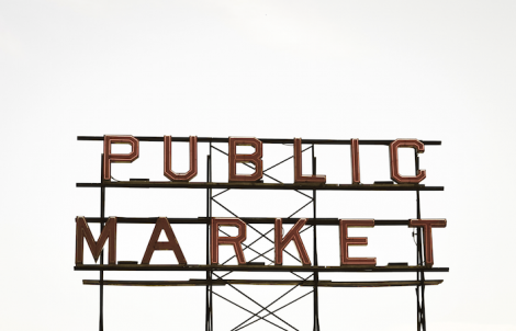 a neon sign that's off that says "public market". the background is a white sky.