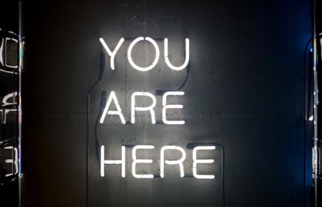 a white neon sign that says "you are here"