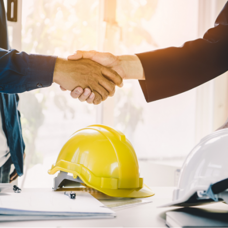 Two people shaking hands over building plans
