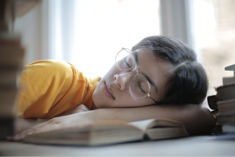 Student sleeping on a book in the library