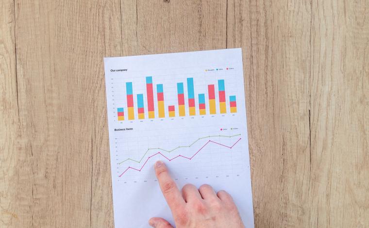 hand pointing at paper with statistics