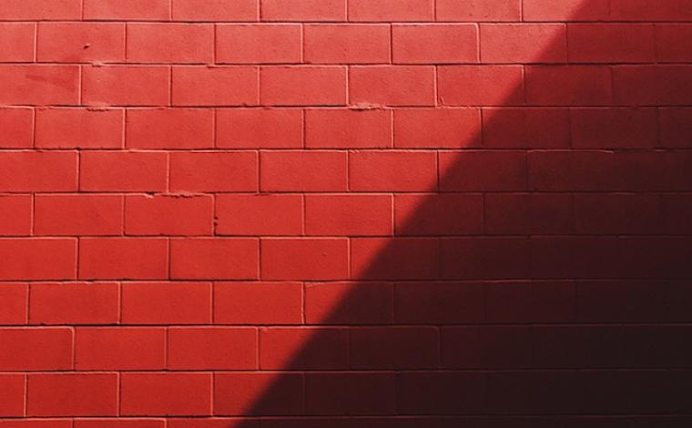 photo of a red brick wall that has the right half of the wall shadowed