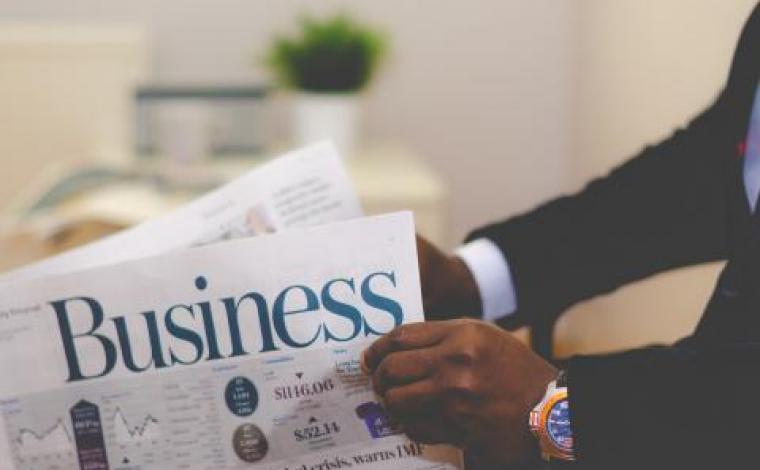 man holding a newspaper that has the word "business" as the title/headline