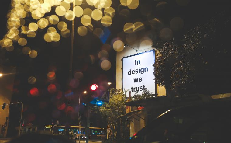 a lit billboard that says "in design we trust"