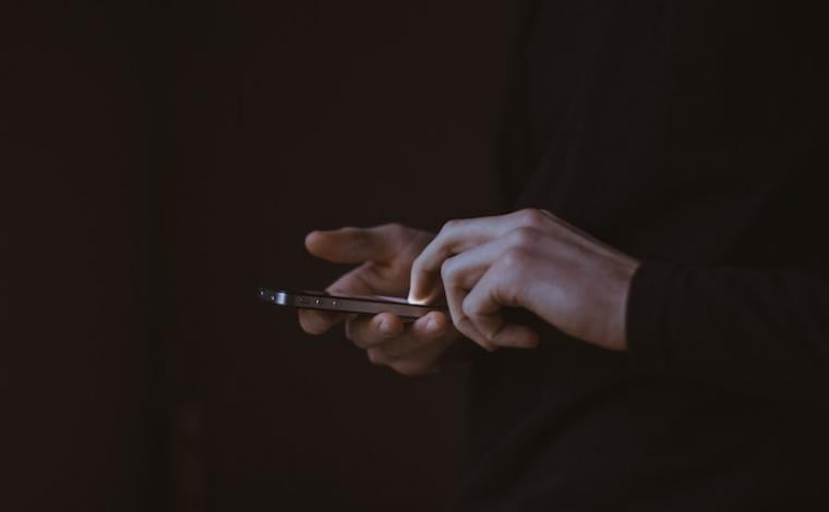 a dark photo of two hands holding a phone