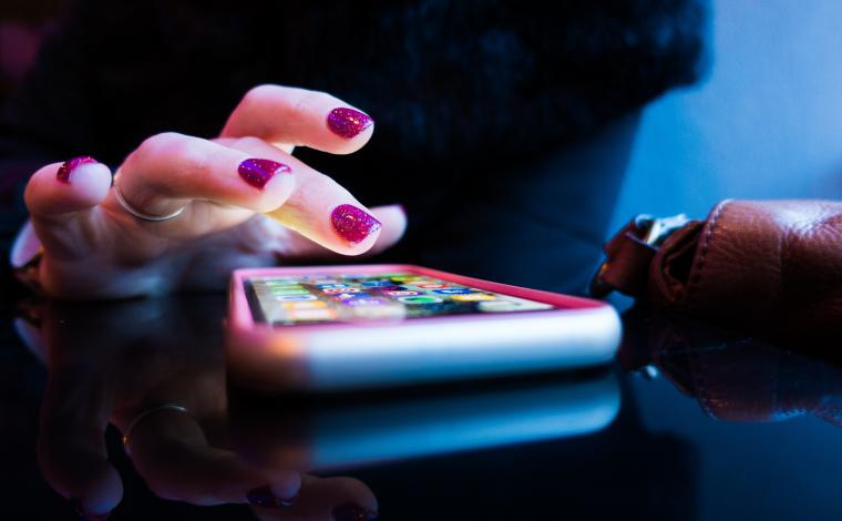 photo of a person with painted nails tapping on a phone