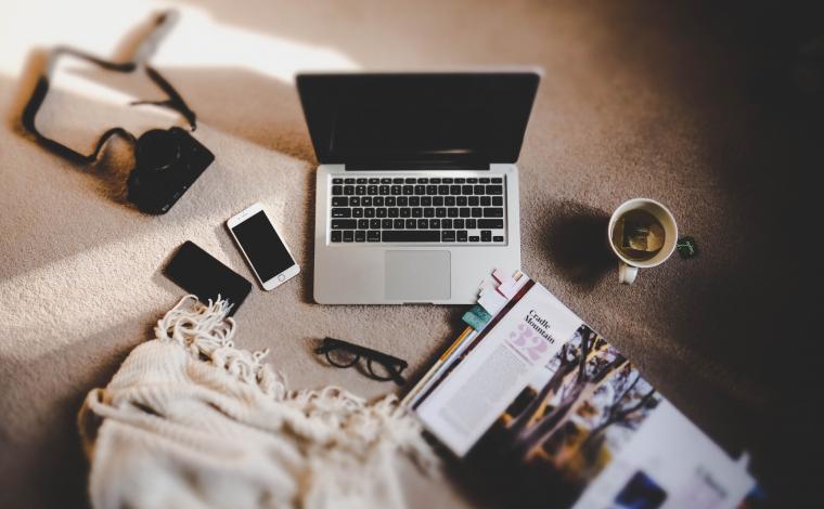 a bird's eye image of an open laptop with various office supplies littered around it