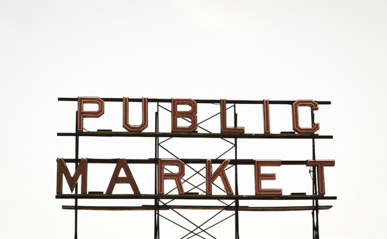 a neon sign that's off that says "public market". the background is a white sky.