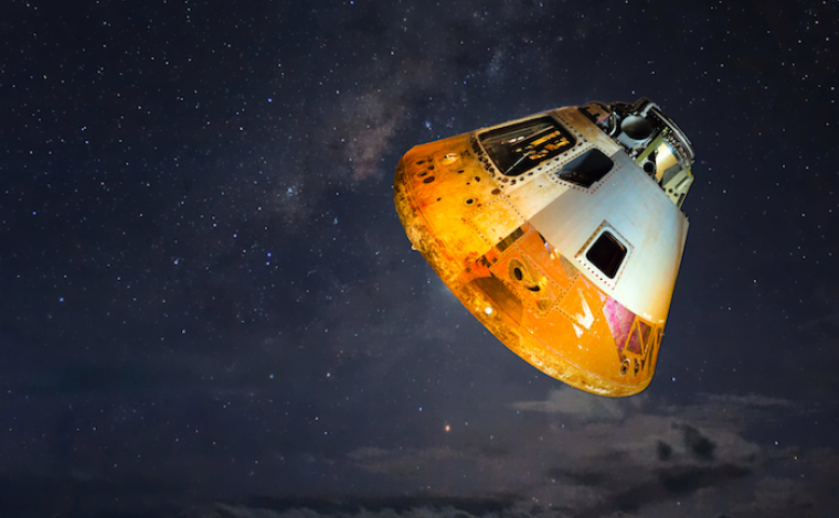 photo of a yellow and grey space capsule floating in a black sky
