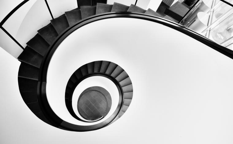 the top of a black spiral staircase contrasted to a white wall around it
