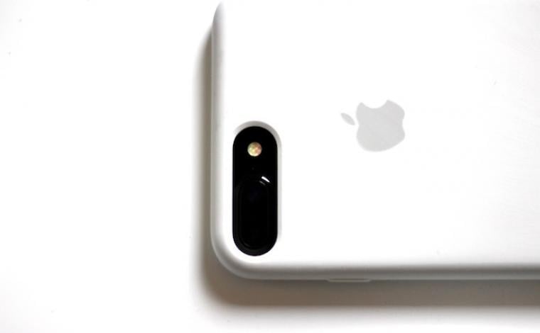 a white iphone with the screen facing down resting on a white surface