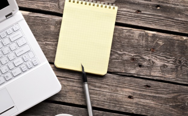 a laptop and an empty notepad laying flat next to each other