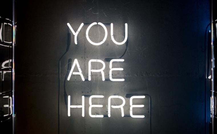 a white neon sign that says "you are here"